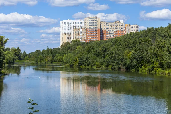 PUSHKINO, RUSIA, 11 de agosto de 2015. Paisaje urbano en la tarde de verano. Casas de varios pisos se reflejan en el río Serebryank — Foto de Stock