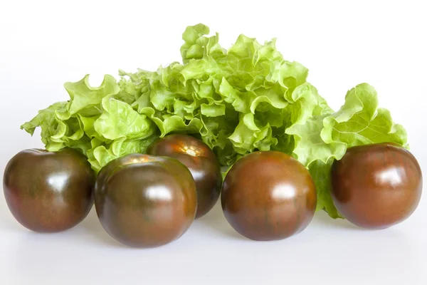 Folhas de salada fresca e tomates pretos — Fotografia de Stock