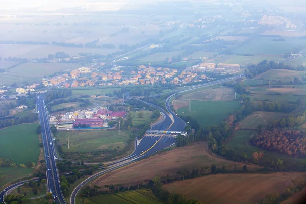 Uitzicht vanuit het raam van de vliegende vliegtuig op wolken en een terrestrische oppervlak hieronder — Stockfoto