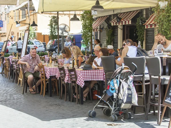 ROME, ITALY, on AUGUST 25, 2015. Picturesque summer cafe on the city street. People have a rest and eat at tables — Stock Photo, Image