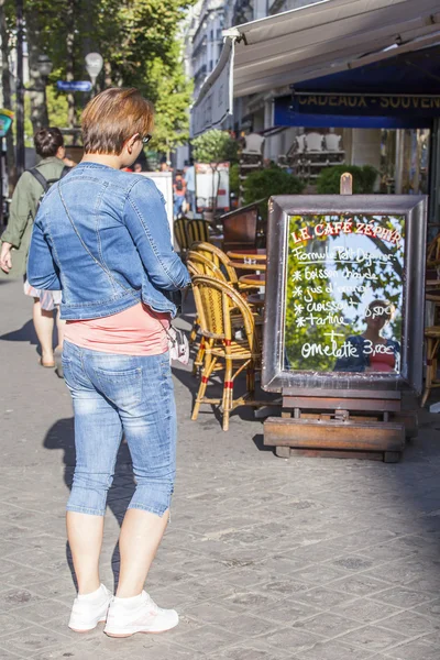 Paryż, Francja, na 26 sierpnia 2015. Kobieta uważa menu letniej kawiarni na ulicy miasta napisane na lustro — Zdjęcie stockowe
