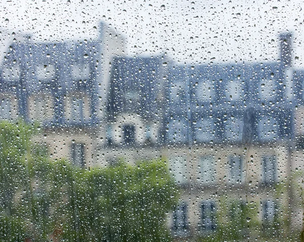 PARIS, FRANCE, on SEPTEMBER 29, 2015. Parisian landscape. A view of city roofs through a wet window during a rain — Stock Photo, Image