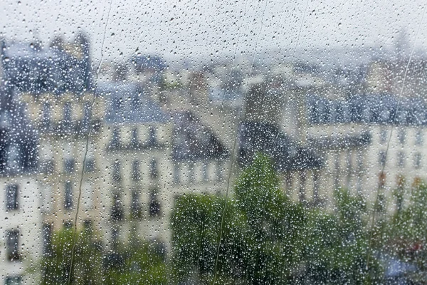 PARIS, FRANCE, on AUGUST 27, 2015. A fragment of an architectural complex of the square in front of the Centre Georges Pompidou, a look through a wet window. It is raining, water drops on glass, focus on drops — стокове фото