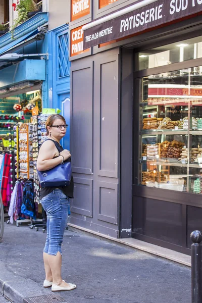 PARIS, FRANCE, on AUGUST 30, 2015. Urban view. Typical Parisian street in the bright sunny day. The woman looks at a show-window of shop of sweets — Zdjęcie stockowe