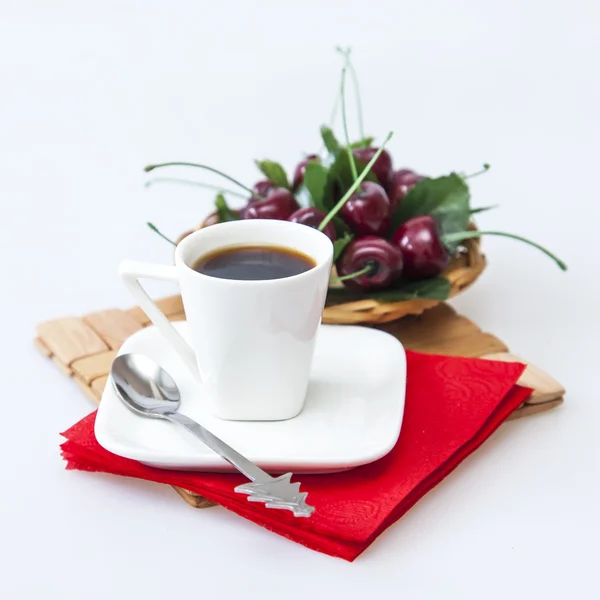 Чашка с черным кофе и тарелка с вишней на заднем плане — стоковое фото