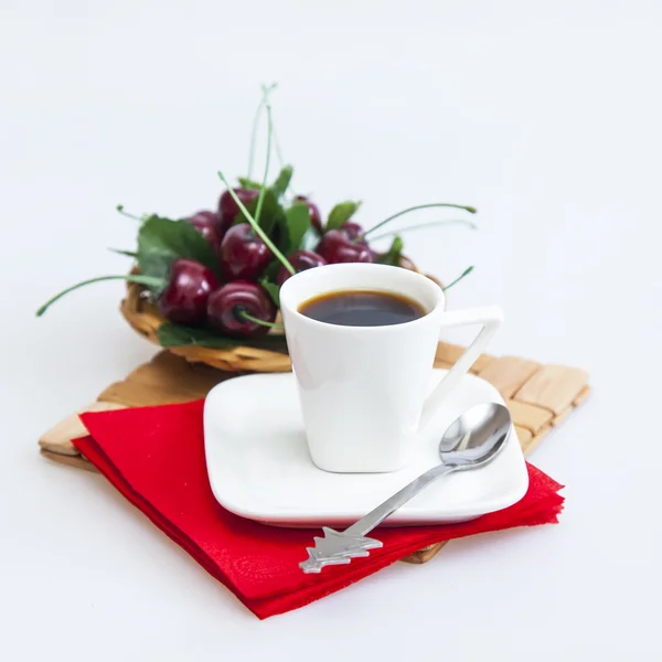 Coupe avec café noir et une assiette avec cerise douce sur un fond — Photo