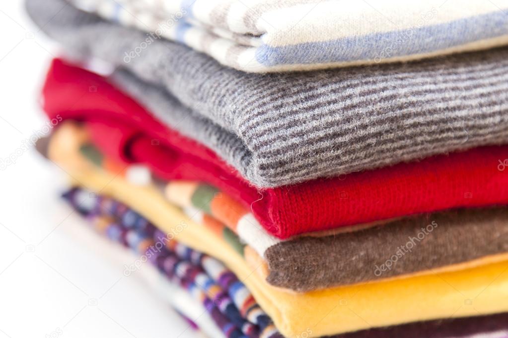 Pile of woolen jumpers of various colors on a show-window of shop