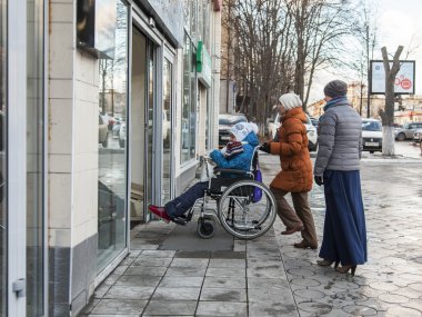 Pushkino, Rusya, 8 Aralık 2015 tarihinde. Mosksvskiy Bulvarı. Kadınlar bir sandalyede engelli kişi ile alışveriş merkezi haline geliyor
