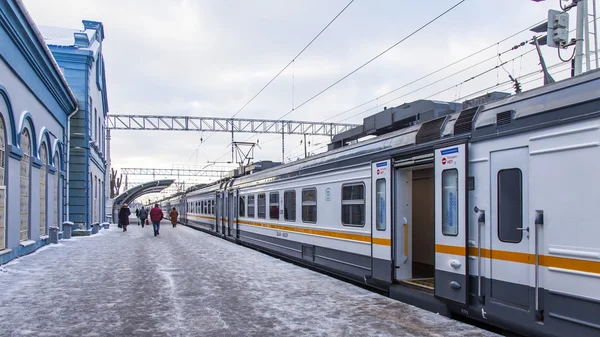 PUSHKINO, RUSSIA, on DECEMBER 17, 2015. Winter day. The suburban electric train stopped at a platform of the railway station. Passengers go on a platform — Stock Photo, Image