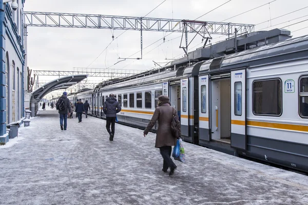 ПУШКИНО, РОССИЯ, 17 ДЕКАБРЯ 2015 г. Зимний день. Пригородный электропоезд остановился на платформе железнодорожного вокзала. Пассажиры идут на платформу — стоковое фото