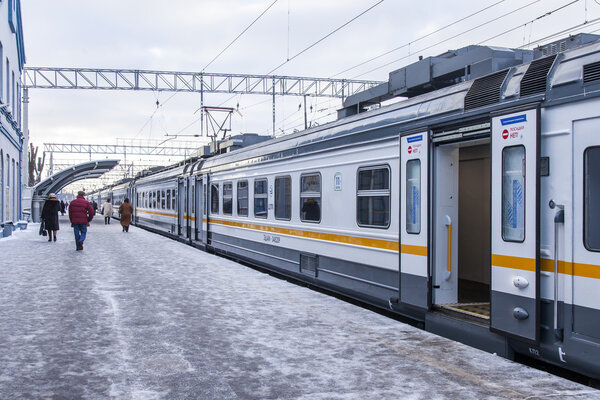 ПУШКИНО, РОССИЯ, 17 ДЕКАБРЯ 2015 г. Зимний день. Пригородный электропоезд остановился на платформе железнодорожного вокзала. Пассажиры идут на платформу

