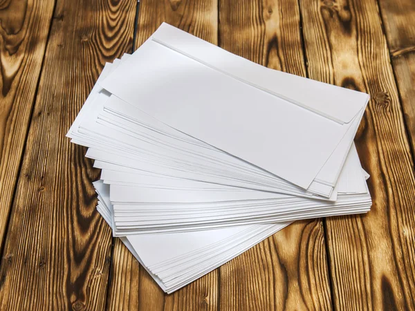 Pilha áspera de envelopes poste branco em uma mesa de madeira — Fotografia de Stock