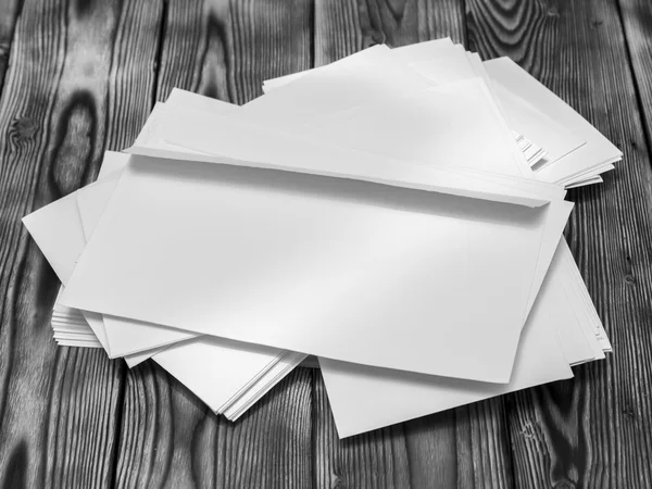 Pilha áspera de envelopes poste branco em uma mesa de madeira — Fotografia de Stock