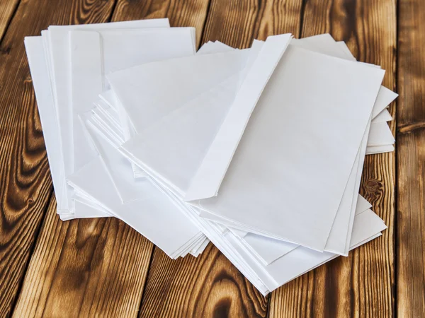 Ruwe stapel van witte post enveloppen op een houten tafel — Stockfoto