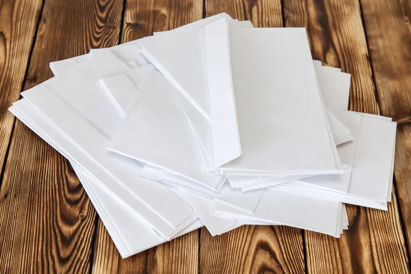 Pilha áspera de envelopes poste branco em uma mesa de madeira — Fotografia de Stock