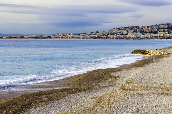 Niza, FRANCIA, en Enero 7, 2016. Una playa y la línea de un oleaje con olas. Arrastramiento en la distancia — Foto de Stock