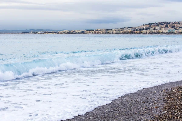 Nice, Frankrike, den 7 januari 2016. En strand och fodra av en surf med vågor. Vallen i fjärran — Stockfoto