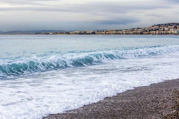 Nice, Frankrike, den 7 januari 2016. En strand och fodra av en surf med vågor. Vallen i fjärran — Stockfoto