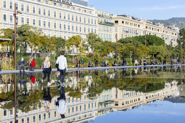 NICE, FRANCE, on JANUARY 7, 2016. The flat fountain in Promenade du Paillon park. An architectural complex of buildings in the boulevard and its reflection in water. People walk on a promenade — Stock Photo, Image