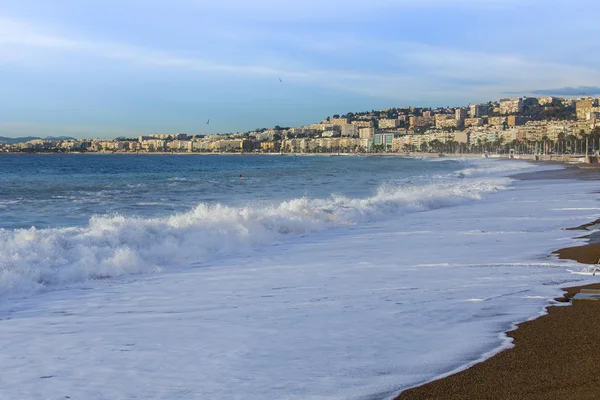 Nice, Frankrike - den 8 januari 2016. Visa av linjen en surfa, våg, beach och sky och vallen i distans — Stockfoto