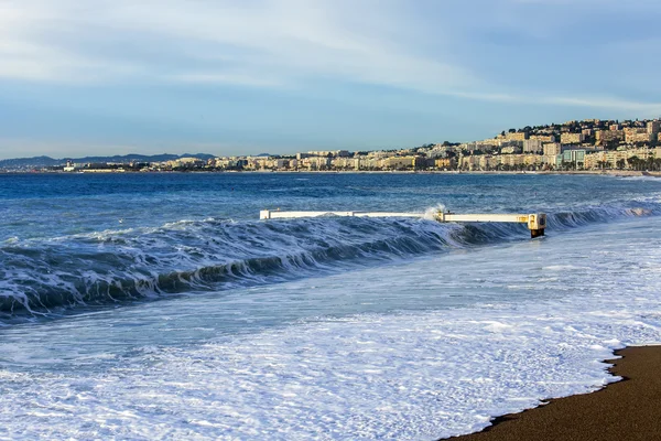 NICE, FRANCIA - el 8 de enero de 2016. Vista de la línea de surf, ola, playa y cielo y terraplén a distancia — Foto de Stock