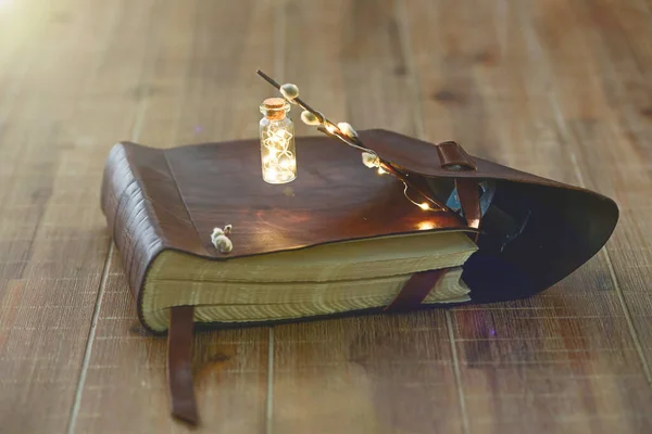 Book with a miniature flashlight lies on a wooden table.