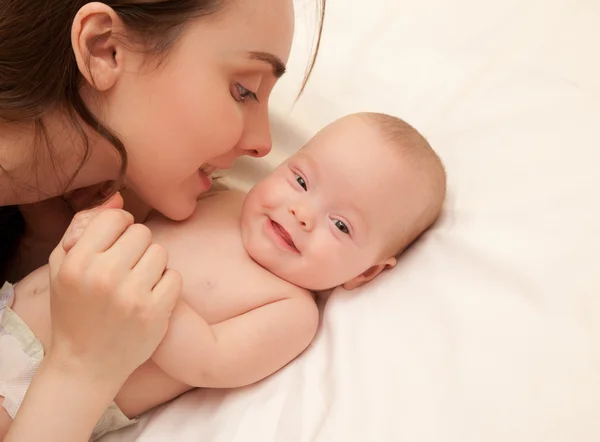 Foto de madre feliz con adorable bebé acostado en la cama — Foto de Stock