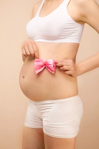 Barriga grávida com arco rosa — Fotografia de Stock