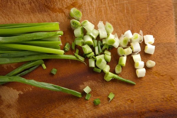 Grüne Zwiebeln auf einem Schneidebrett — Stockfoto