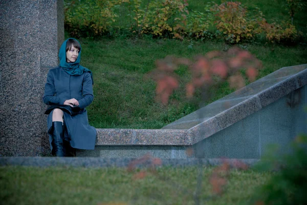 Vackra eleganta kvinnan i grå kappa sitter utomhus — Stockfoto