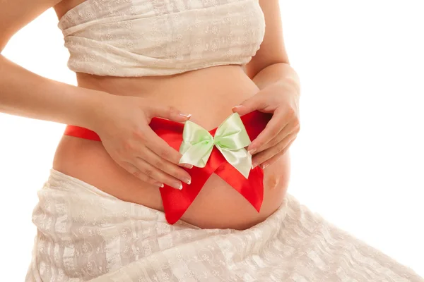 Barriga de mulher grávida com fita vermelha — Fotografia de Stock
