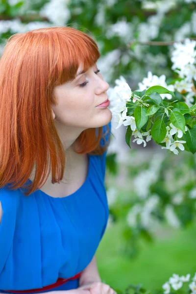 Mooie vrouw in blauwe jurk in de buurt van appelboom Stockfoto