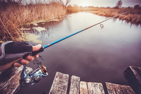 Hombre sosteniendo varilla giratoria en el río. pesca — Foto de Stock