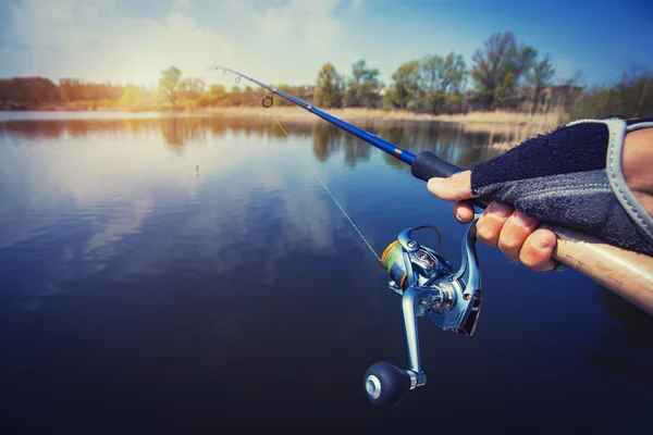 Mano con filatura e mulinello sul lago estivo serale — Foto Stock