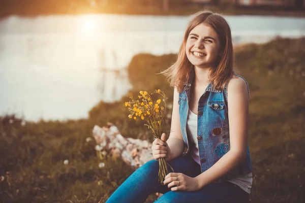 Ung flicka i parken med blommor — Stockfoto