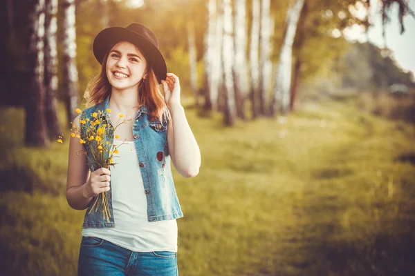 Mladá dívka v parku s květy — Stock fotografie