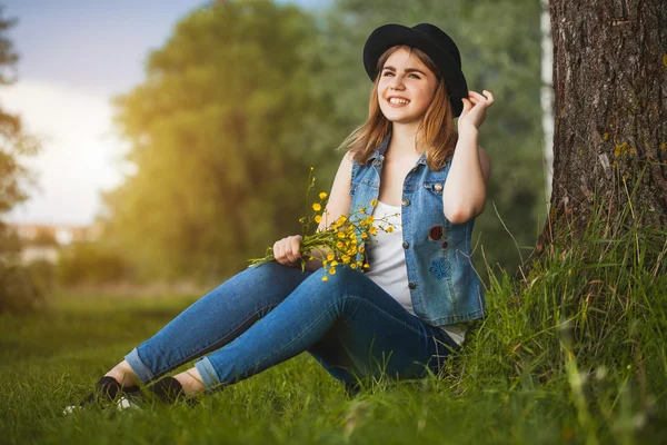 Ung flicka i parken med blommor — Stockfoto