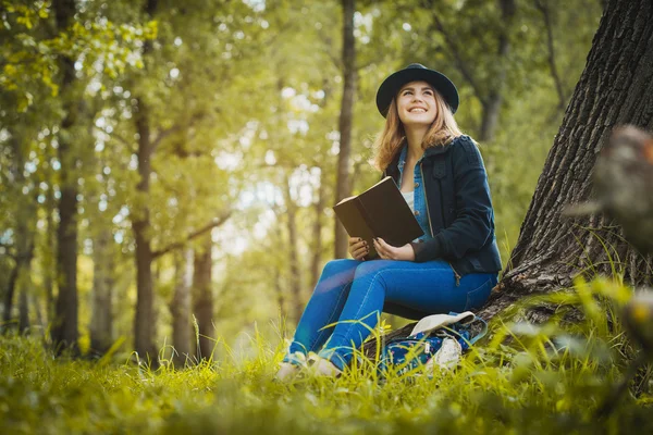Relaxed girl reading an book under a tree — Stock Photo, Image