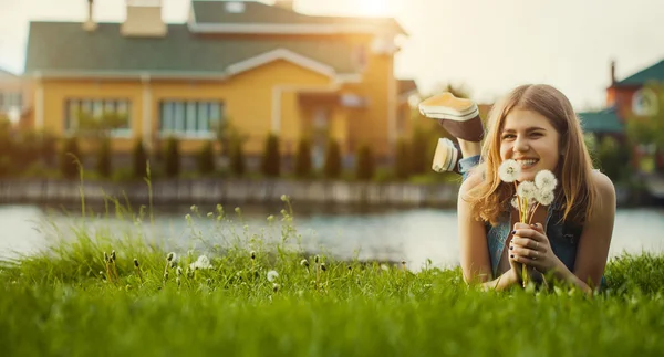 Jong meisje met paardebloem in lentetuin. — Stockfoto