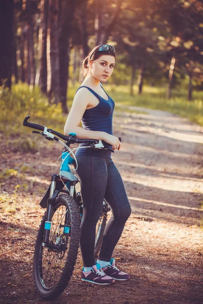 Vrouw fietser rijdt in het bos op een mountainbike. — Stockfoto