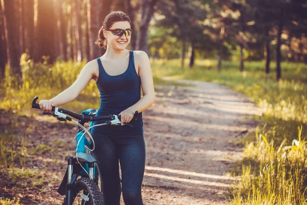 Donna ciclista cavalca nel bosco in mountain bike . — Foto Stock