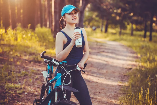 Young happy woman on bike resting drinking water — Stock Photo, Image