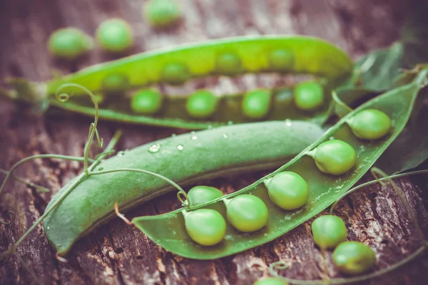 Pois verts sur fond de bois brun. — Photo