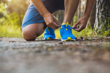 Ayakkabı bağcıklarını spor ayakkabılarına bağlayan koşucu.