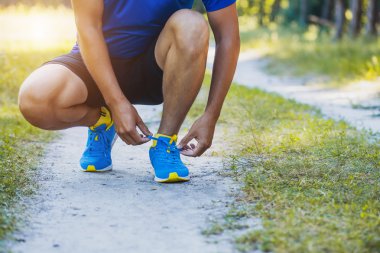 Ayakkabı bağcıklarını spor ayakkabılarına bağlayan koşucu.