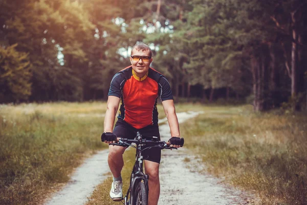 Człowiek rowerzysta jeździ się w lesie na rower górski. — Zdjęcie stockowe