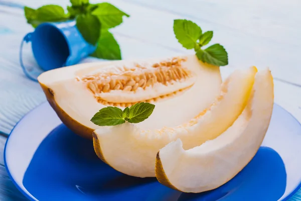 Melón dulce fresco en plato azul sobre la mesa de madera blanca — Foto de Stock