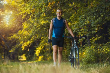 Bisikletli adam orman yolunda gidiyor.