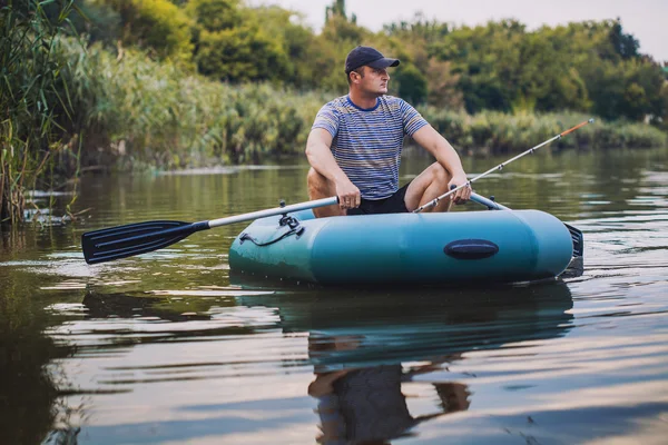 Mann angelt aus dem Schlauchboot auf dem Teich — Stockfoto