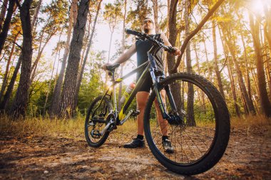 Bisikletli adam orman yolunda gidiyor.